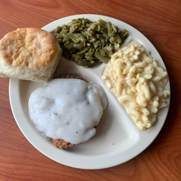 A Barge Inn American meal with chicken fried steak, gravy, green beans, macaroni and cheese, and a biscuit.